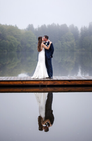 Couple kissing on the dock, reflecting in the water