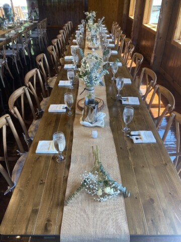 Rustic wooden table with burlap runner down the middle.