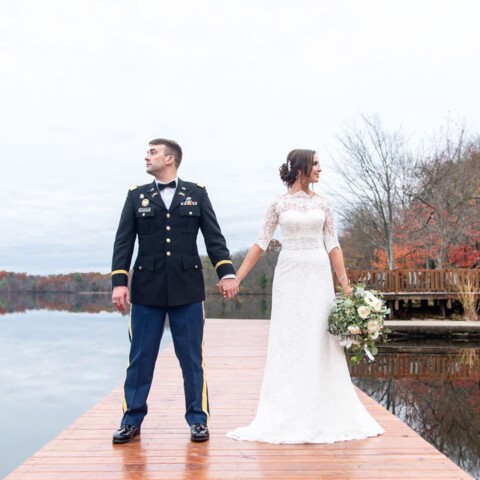 Military couple holding hands on dock.