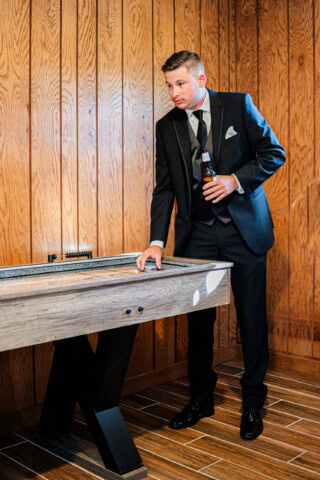 Groomsman plying shuffleboard in wedding suite