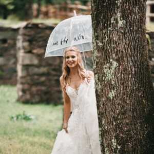 Bride holding umbrella next to stone foundations.