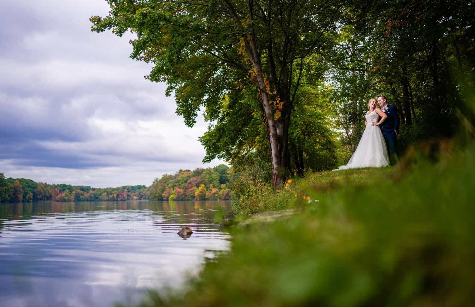 bride and groom couple next to a lake.