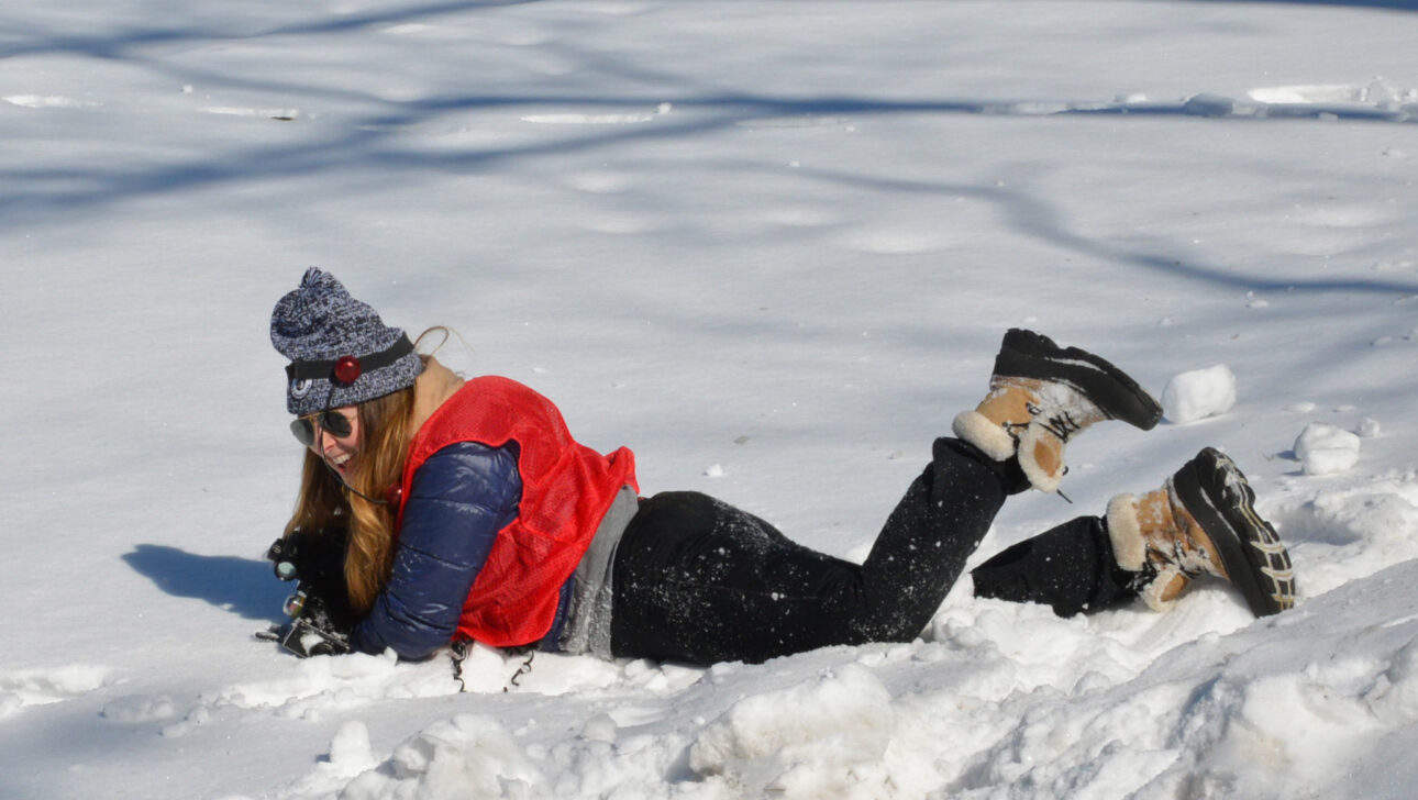 woman laying in snow playing laser tag.