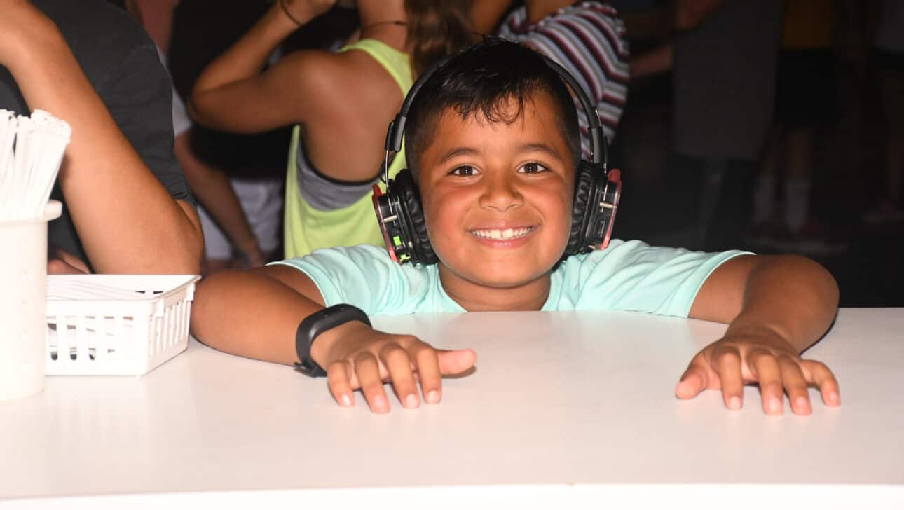 boy smiling at table during silent disco.