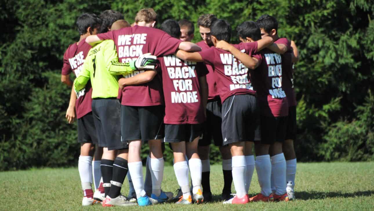 boys in soccer huddle with tshirts that say were back for more.