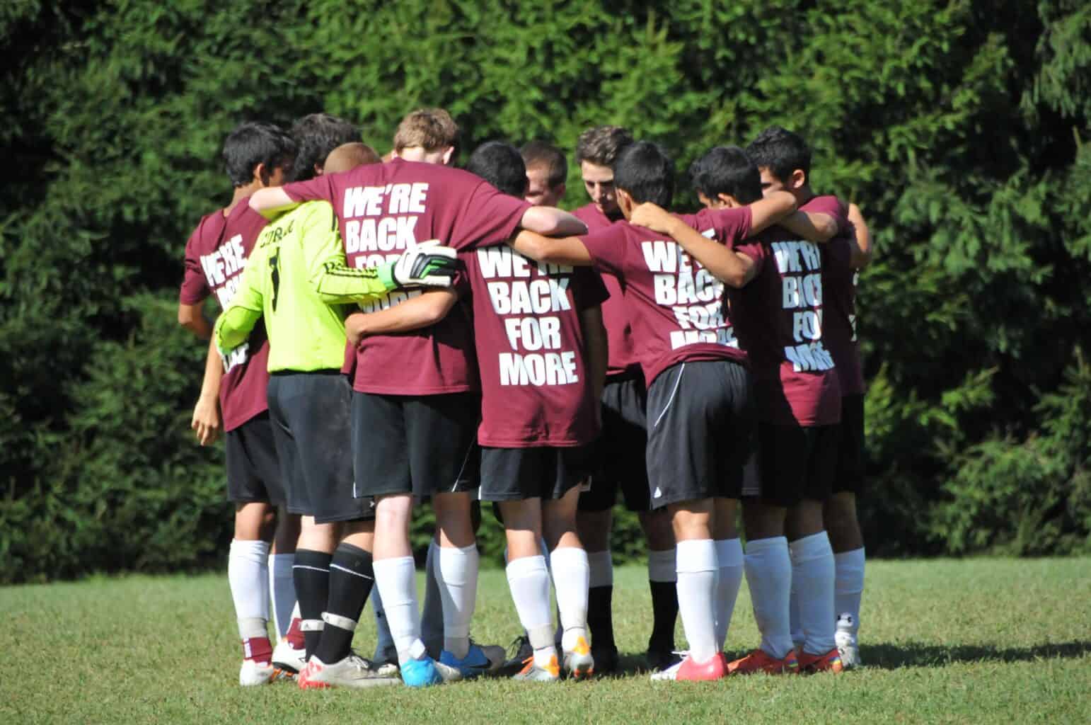Boys in soccer huddle with tshirts that say were back for more.