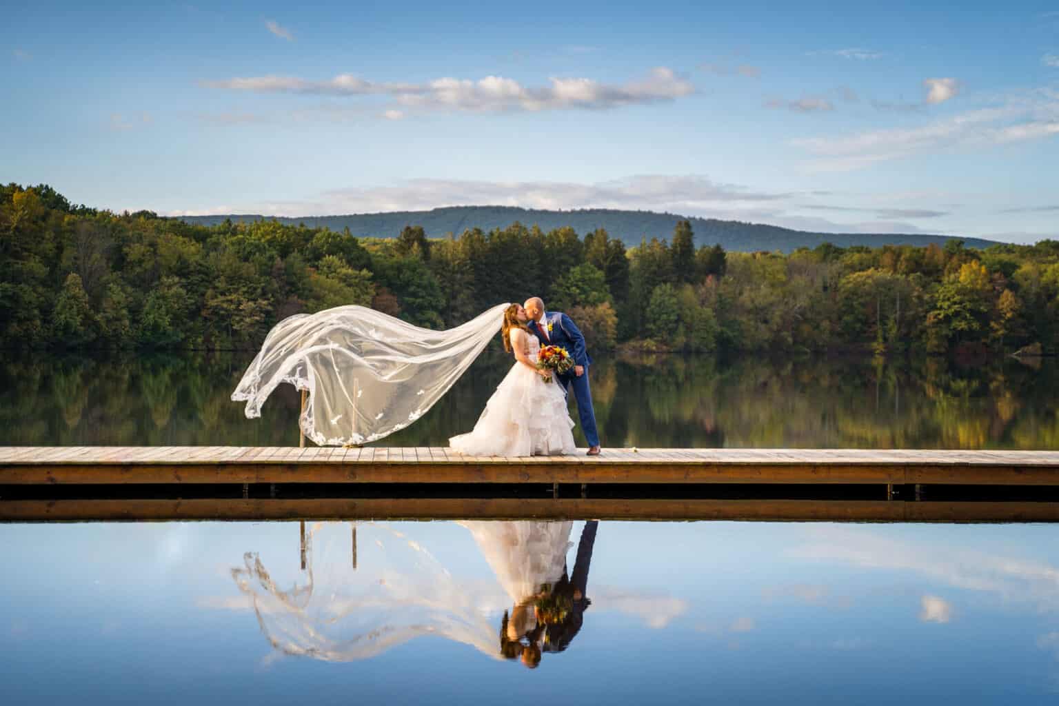 a bride and groom on a dock on a lake.