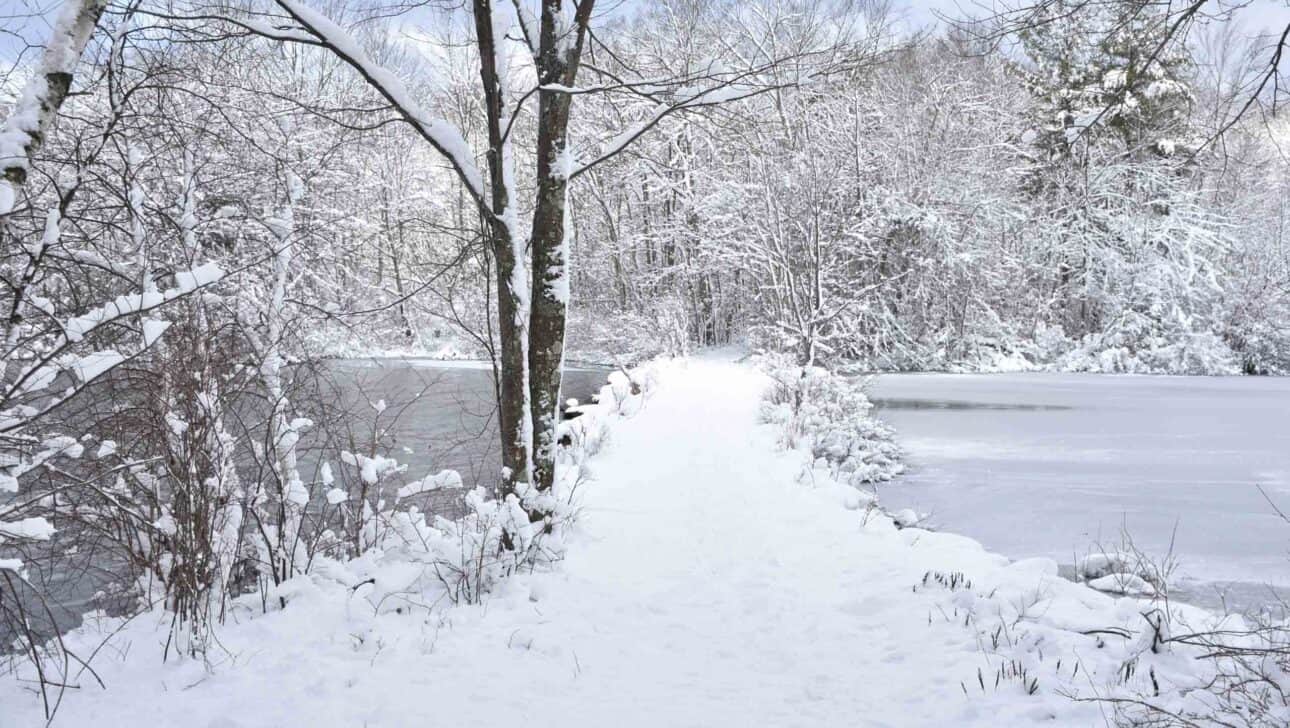 snow covered walking path over lake.