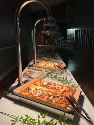 pizza stations with tongs in a dark room.