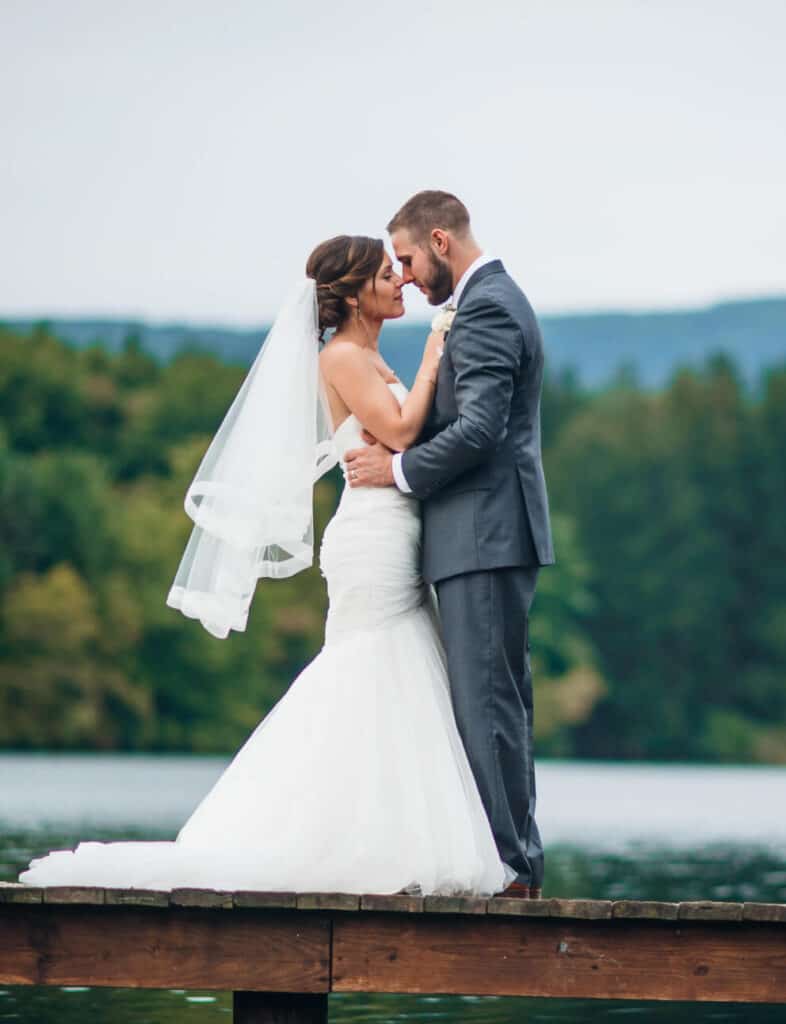 bride and groom on a dock on a lake.