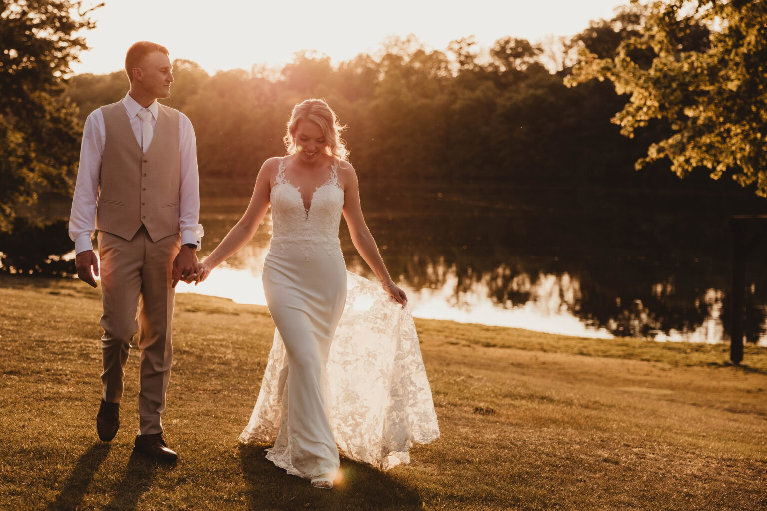 Bride & Groom walking lakeside during golden hour.