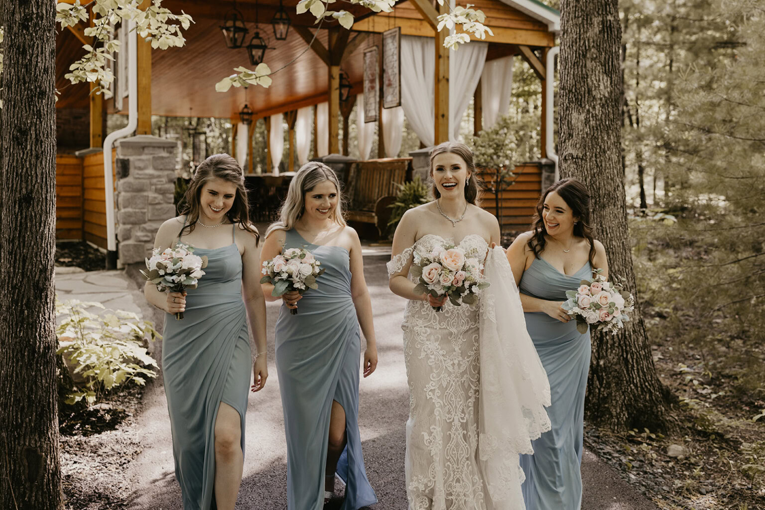 Bride and bridesmaids walking in front of the woodland pavilion.