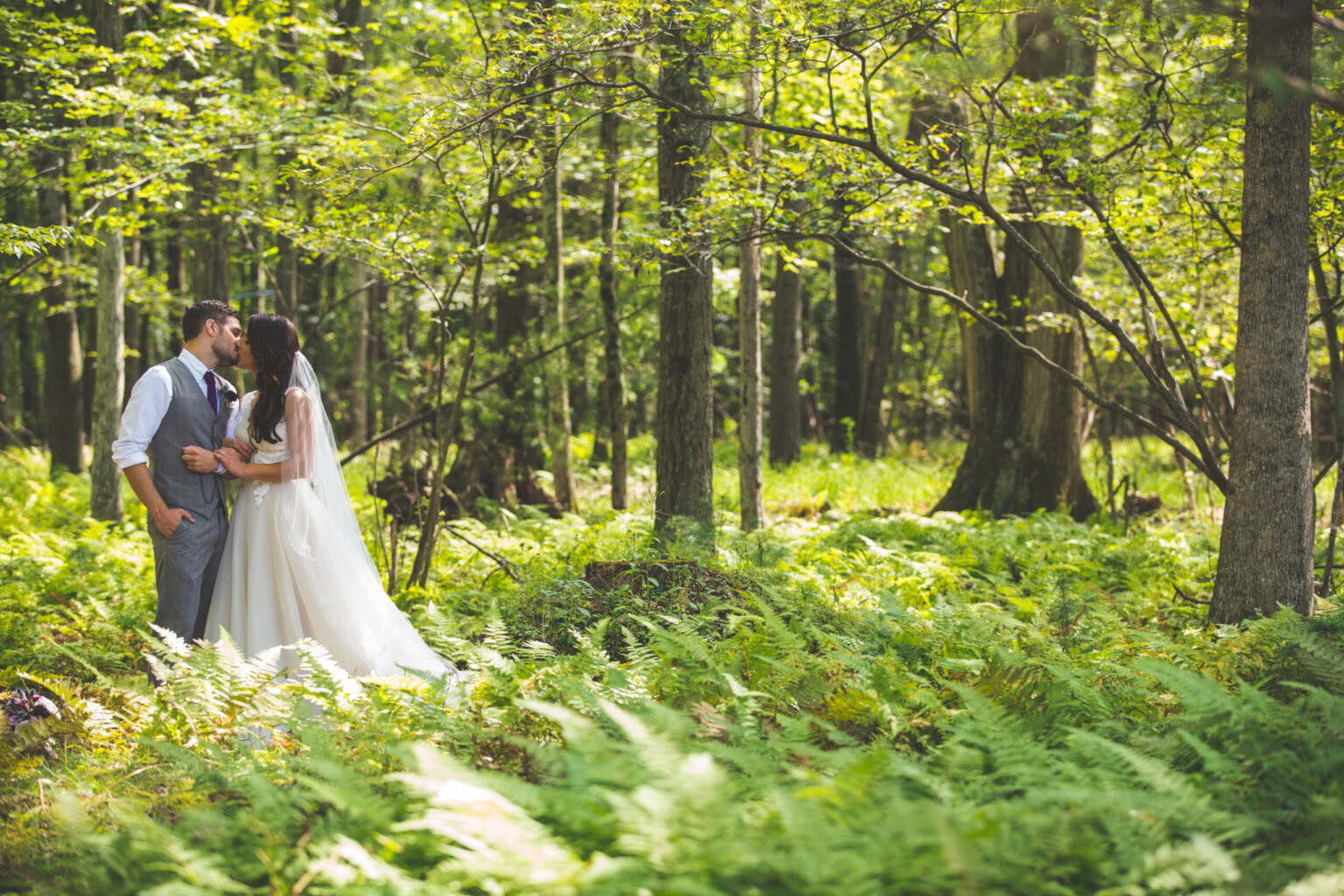 Couple kissing surrounded by woodland ferns.