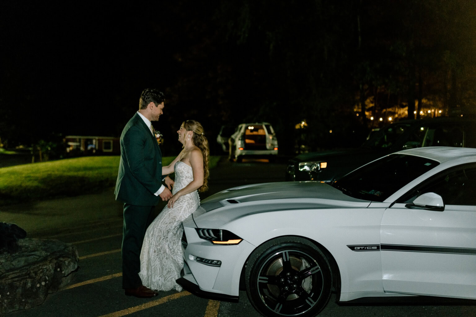 Couple leaning against the hood of their car.