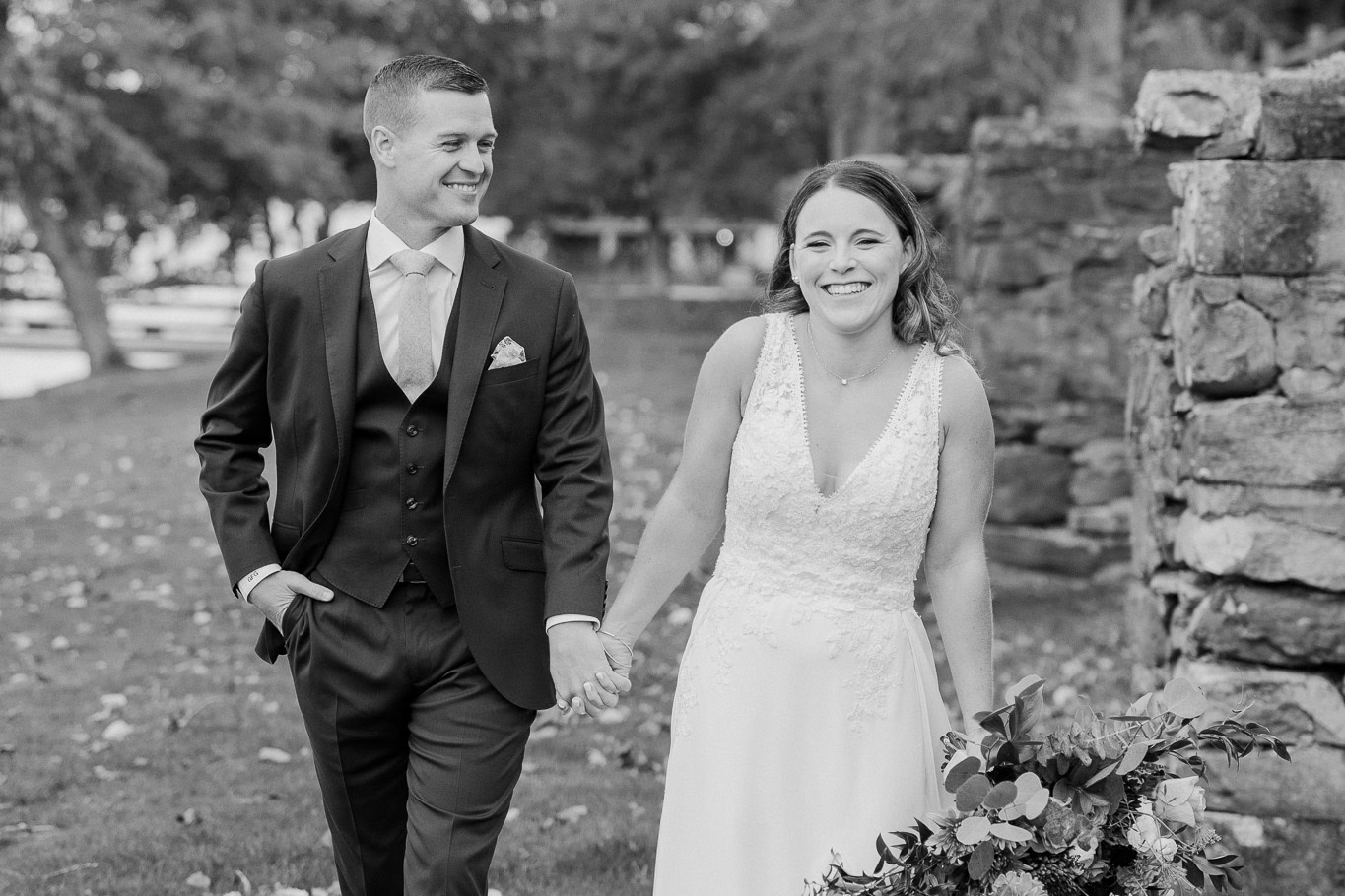 Black and white photo of couple walking alongside the stone foundations