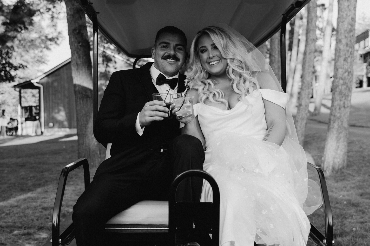 Black and white photo of couple toasting on the back of a golf cart