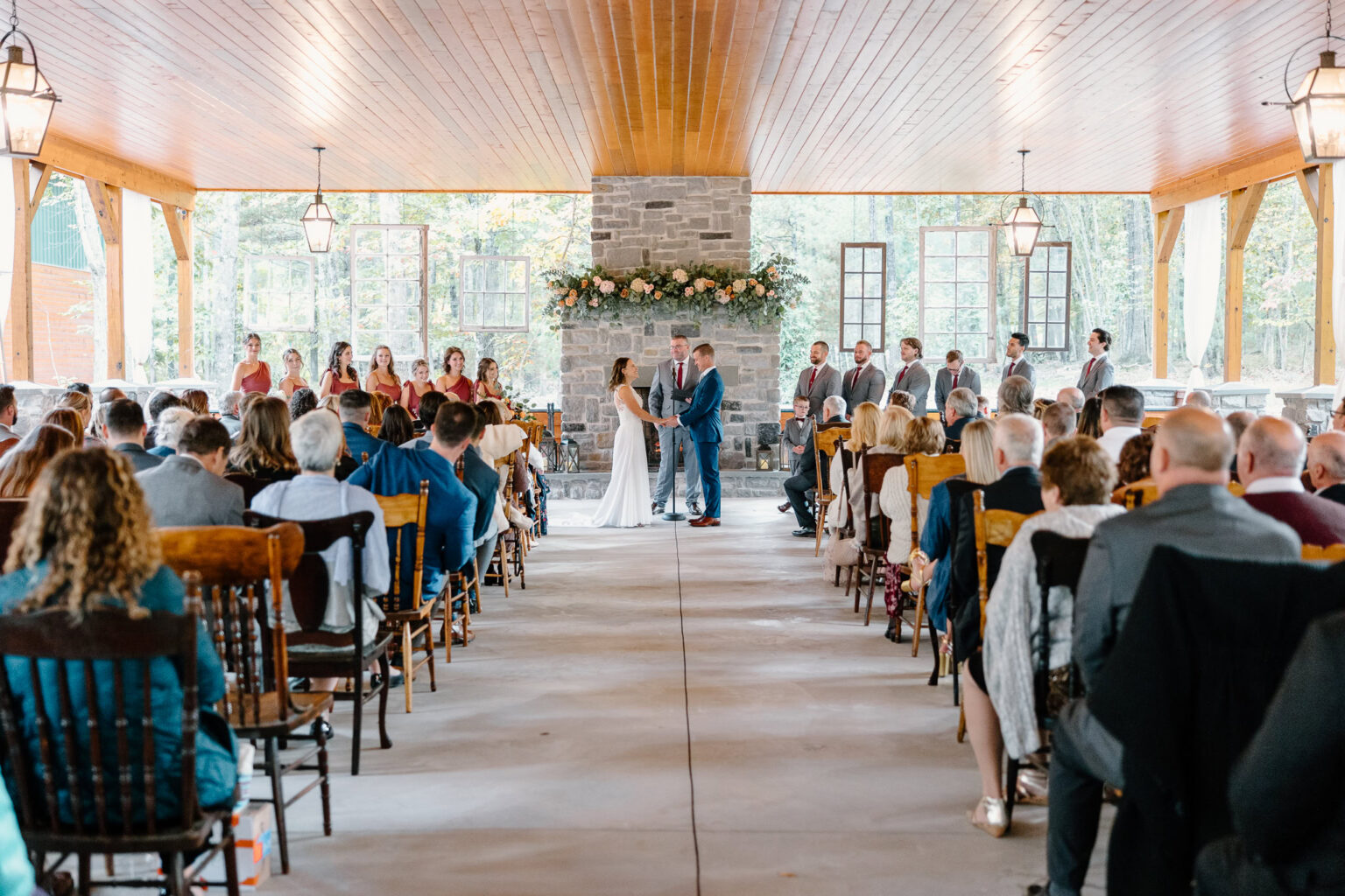 Couple holding hands during their ceremony in front of the pavilion fireplace