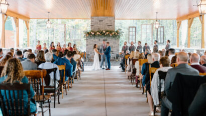Couple holding hands during their ceremony in front of the pavilion fireplace
