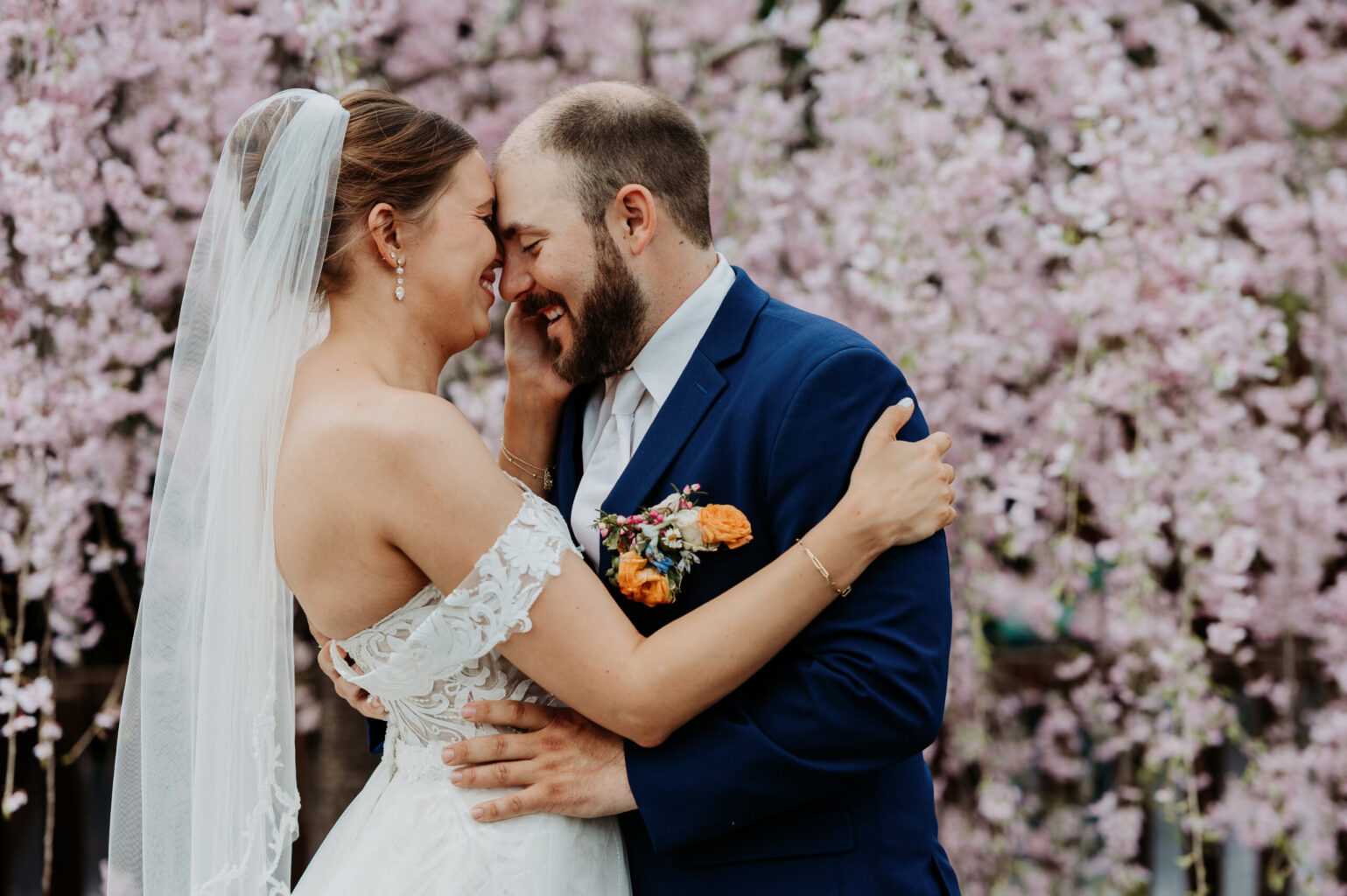 Couple embrace in front of a blossoming tree