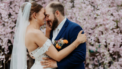 Couple embrace in front of a blossoming tree