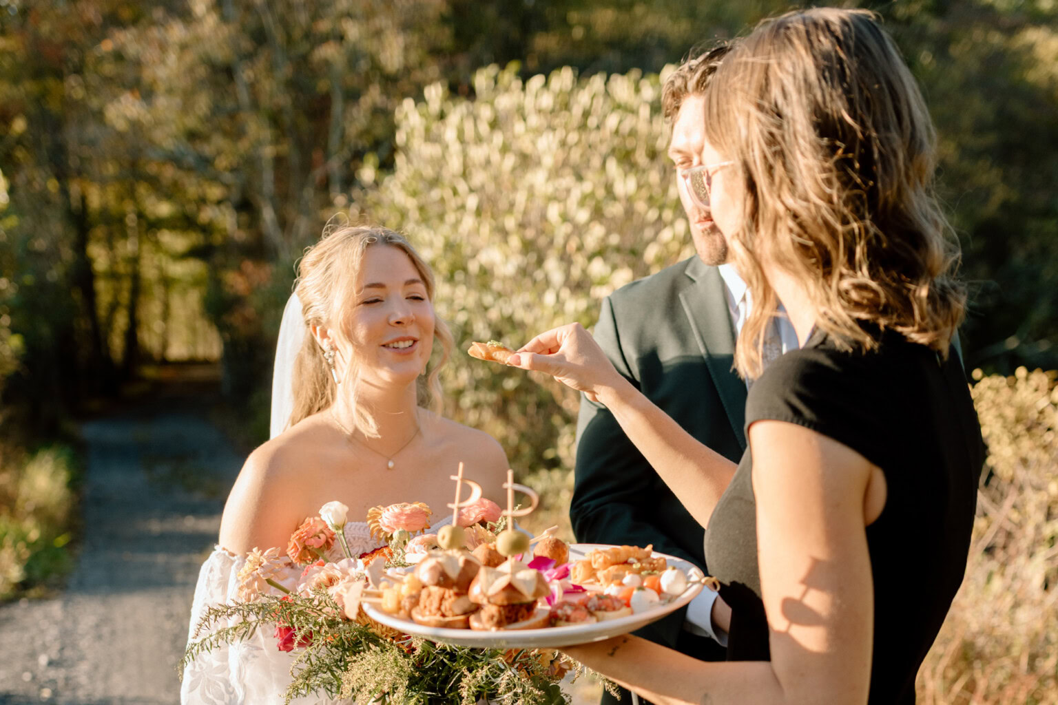 Bridal attendant offering hors d'ouevres to couple