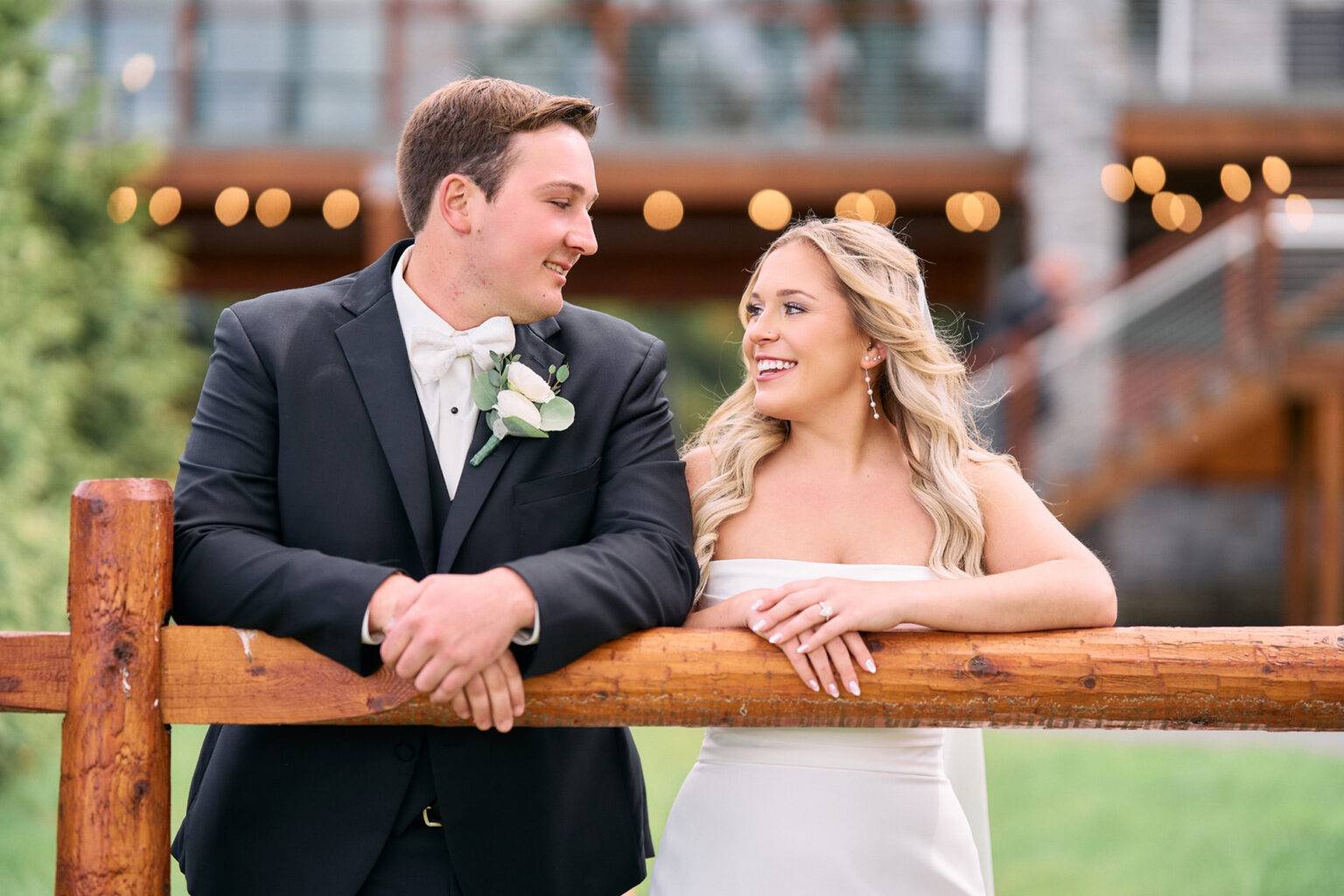 Couple smiling and talking while leaning against the wooden fence.